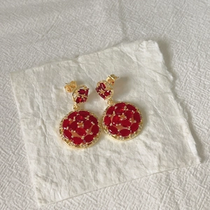 Detailed macro view of 18k gold earrings with sparkling red zircon crystals