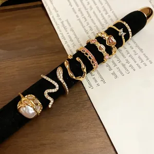 Set of 7 gold rings with heart, pearl, and butterfly designs on a velvet display stand