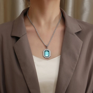 Hiphop silver chain necklace with blue sapphire square pendant worn by a model