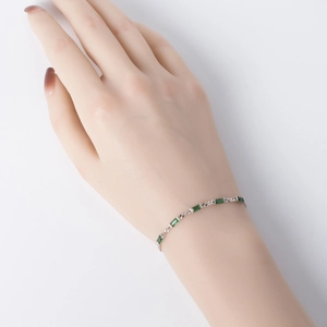 Detail shot of a silver S925 bracelet featuring elegant green baguette-cut gemstones