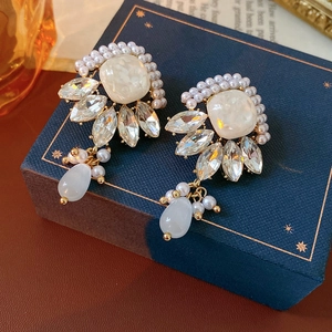 Dettaglio di orecchini vintage dorati con perle su una scatola di gioielli blu