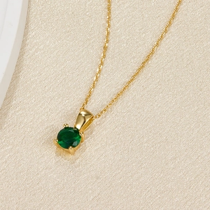 Macro shot of 925 silver necklace featuring a round green gemstone in gold four-prong setting