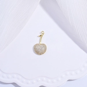 Elegant gold cherry pendant with pave-set cubic zirconia on white textured fabric