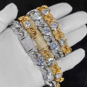 Detail van gouden en zilveren Cubaanse schakels met glinsterende hartvormige zirkoon