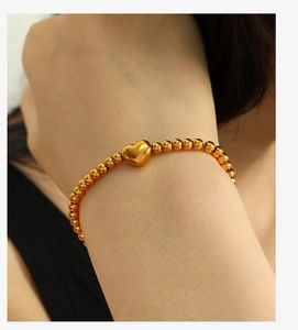 Détail du bracelet à billes plaqué or 18k avec pendentif coeur minimaliste au poignet