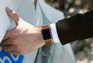 Close-up of brown leather watch band with magnetic buckle on wrist by a white car