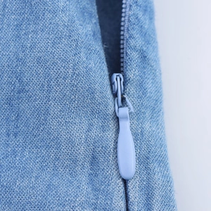 Vue détaillée du tissu denim bleu clair avec une fermeture éclair métallique invisible