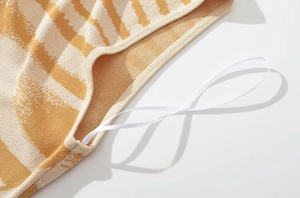 Dettaglio dell'abito in maglia giallo e bianco con motivo astratto e cuciture tagliacuci