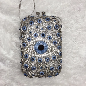 Detailed view of silver evil eye crystal clutch bag with blue rhinestones and chain strap