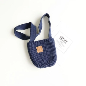 Dettaglio borsa a tracolla in maglia blu scuro con toppa in pelle marrone e tracolla tessuta