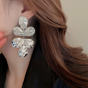 Macro detail of silver hammered flower earrings with abstract floral drop design