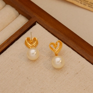 Vintage hollow heart earrings with white pearls and gold finish on wood display