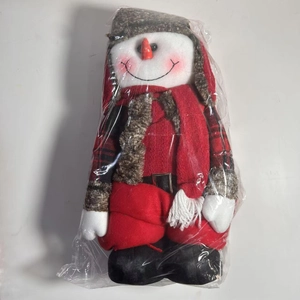Close-up of a plush snowman figurine with red plaid hat and scarf in clear packaging