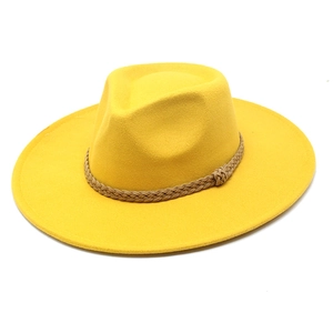 Dettaglio di un cappello di lana giallo con nastro di corda marrone intrecciato chic