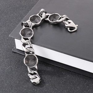 Retro stainless steel Cuban chain bracelet featuring skull charms on a black book