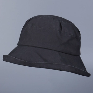 Detailed close-up of a plain black cotton bucket hat showing fabric texture and curved brim