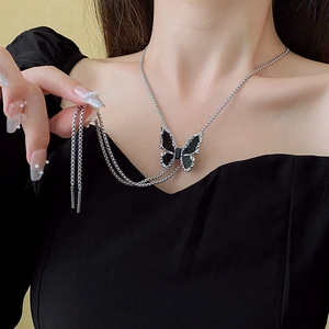 Close-up of double-layer silver chain necklace with a black butterfly pendant on neck