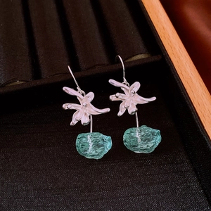 Detail view of flower resin drop earrings with blue-green stone on jewelry box