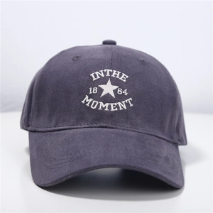Close-up of embroidered IN THE MOMENT text on dark grey cotton twill baseball cap