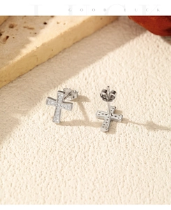 Detailed view of silver cross stud earrings with sparkling pavé stones on a stone base