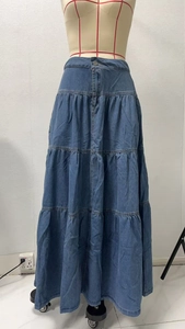 Dettaglio di gonna in denim a balze multistrato con bottoni in metallo e lavaggio