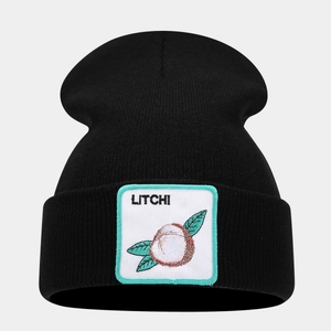 Detailed close-up of a black knit beanie with a square embroidered litchi fruit patch