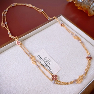 Dettaglio collana a doppia catena dorata con ciondolo a quadrifoglio rosa e perle