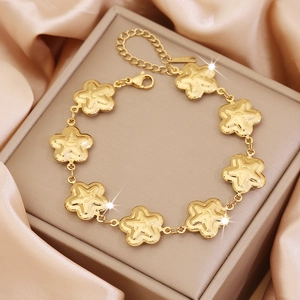 Close-up of golden flower charm bracelet displayed on a luxury satin jewelry box