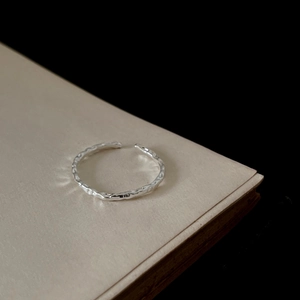 Minimalist S925 sterling silver open ring with textured hammered finish on a beige book