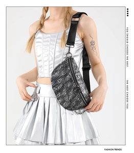 Detail of crossbody bag with silver skull pattern, chain decoration and black wide strap