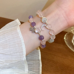 Detail of beaded bracelets featuring crystal stones, butterfly and moon charms on a wrist