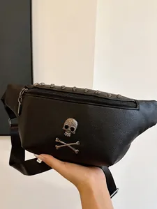 Minimalist black leather belt bag with large silver skull emblem and wide shoulder strap