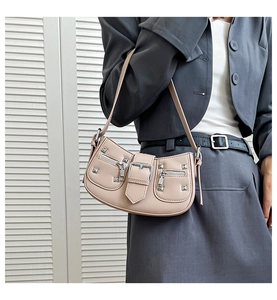 Detail of beige shoulder bag with silver studs and metal buckle on grey blazer