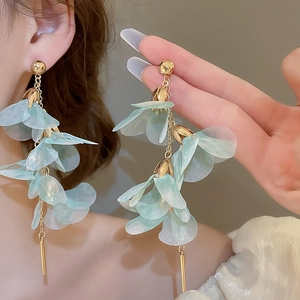 Détail de longues boucles d'oreilles à pétales en maille bleu clair avec pompon doré