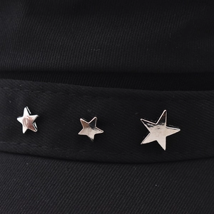 Détails de rivets étoiles argentés sur le tissu sergé noir d'un béret de mode chic