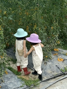 Vista dettagliata di cappelli di paglia per bambini e salopette in un ambiente da giardino