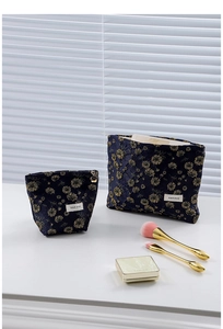 Close-up of navy velvet cosmetic bags with gold daisy patterns and H&R BAG logo