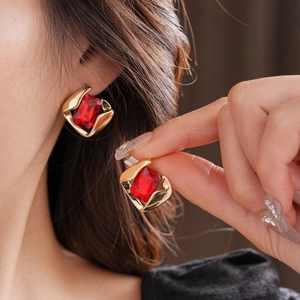 Detailed view of red square gemstone earrings with golden frames on a female model