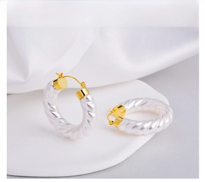 Detailed macro of pearl white spiral hoop earrings with elegant gold metal fasteners