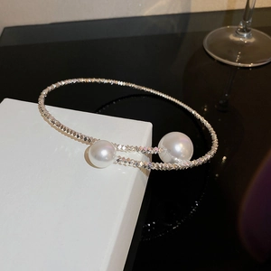 Close-up of a silver-toned textured choker necklace with two white pearls on a white stand