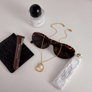 Nahaufnahme einer 18K vergoldeten Kette mit Barockperle und Schildpatt-Sonnenbrille
