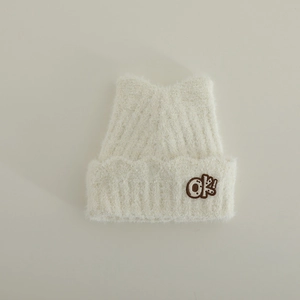 Close-up of cream cat ear knit hat featuring a fuzzy texture and OK! letter patch
