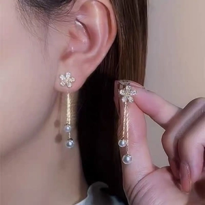 Detailed shot of floral stud earrings with dangling long chains and white pearls
