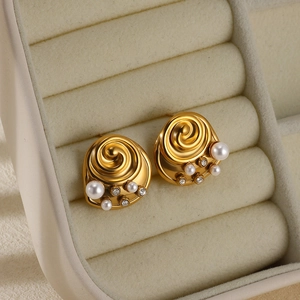 Detailed shot of golden spiral stud earrings with white pearls and rhinestones