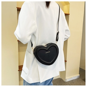 Dettaglio della borsa a tracolla a forma di cuore con cerniere dorate e scritte fashion