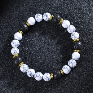 Detail of white turquoise and lava stone bead bracelet with golden metal accents