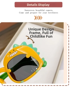 Close-up of yellow dinosaur sunglasses frame with green spikes and dark protective lenses