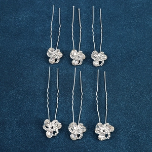 Detailed view of six silver U-shaped hair pins with sparkling floral rhinestone accents