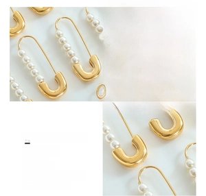 Detailed macro view of gold-plated safety pin earring featuring white inlaid pearls