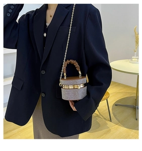 Detail of a sparkling rhinestone cylinder bag with brown leather pleated handle and chain